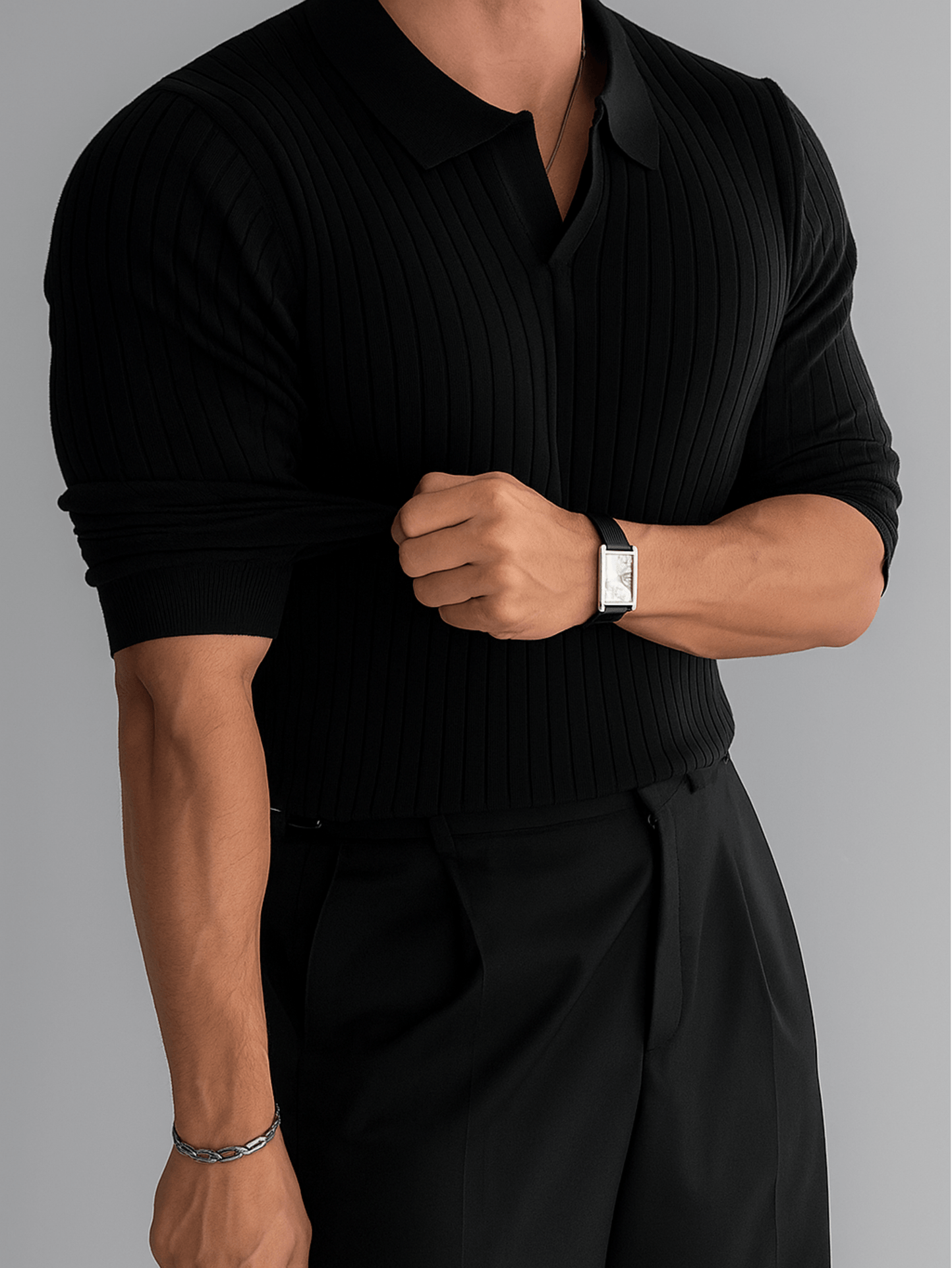 Zwarte ribgebreide polo trui voor heren met opgerolde mouwen, gecombineerd met zwarte pantalon.