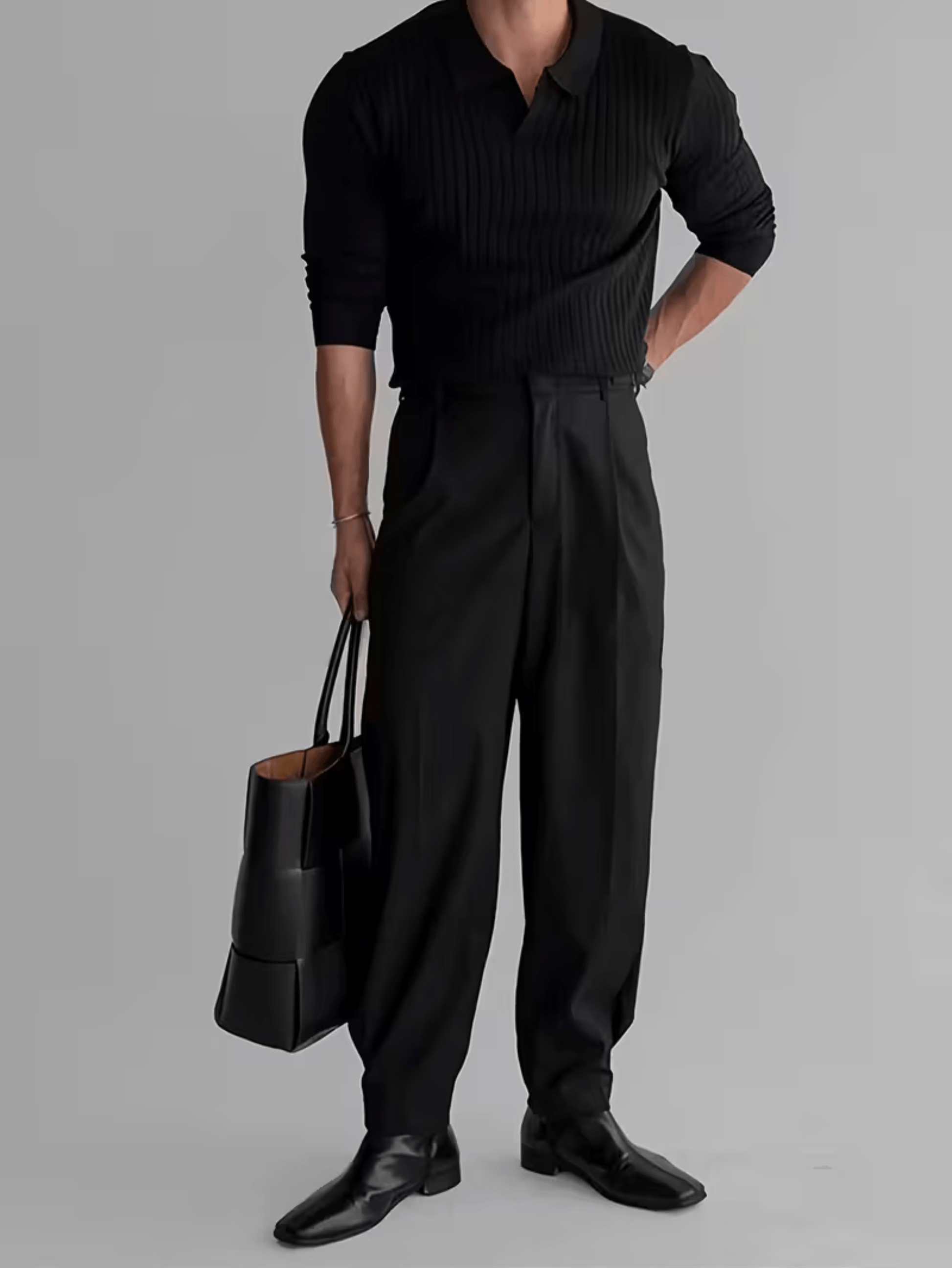 Zwarte ribgebreide polo trui met lange mouwen, gedragen met zwarte pantalon, leren tas en nette schoenen.